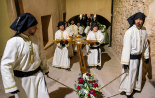Santa Cruz llevada por cuatro cofrades de la hermandad pasando por debajo del arco de la iglesia de la Asunción de Tobarra