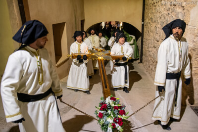 Santa Cruz llevada por cuatro cofrades de la hermandad pasando por debajo del arco de la iglesia de la Asunción de Tobarra