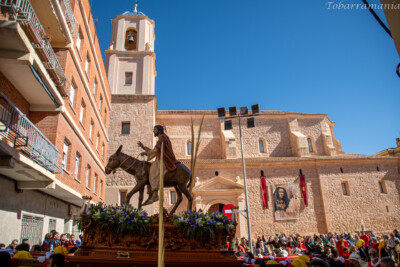 trono e imagen de la Entrada triunfal de jesús en jerusalén (burrica) con la Iglesia de la Asuncion de fondo. Tobarra