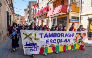 Niños vestidos de tamborileros llevando la pancarta de la Tamborada Escolar de Tobarra en el miércoles Santo de 2023