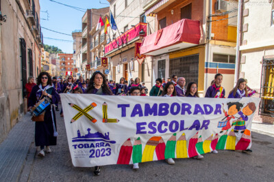 Niños vestidos de tamborileros llevando la pancarta de la Tamborada Escolar de Tobarra en el miércoles Santo de 2023