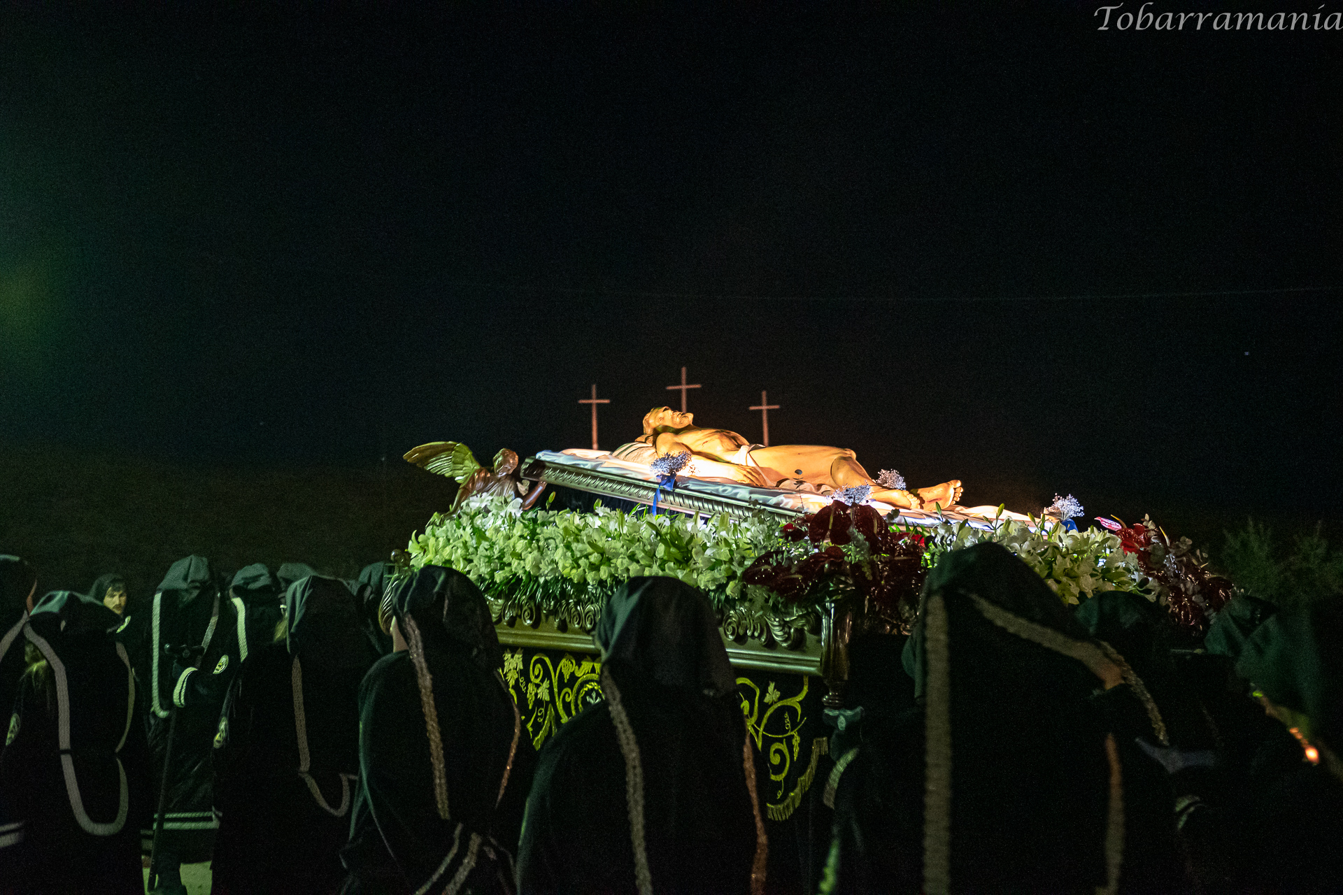 El santo sepulcro sube a la Cima del Calvario de Tobarra para que se lleve a cabo el acto del Entierro, Tras él se ven las tres cruces que hay en el monte. Viernes Santo por la noche. Semana Santa de Tobarra